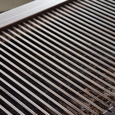 Ein sauberer silberner Grillrost mit vereinzelten dunklen Rückständen darunter