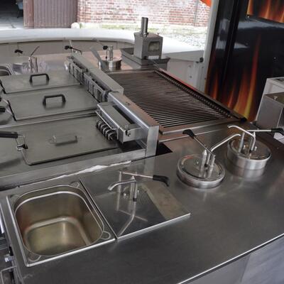 Ein moderner Imbissstand mit silbernen Edelstahloberflächen und mehreren Grillgeräten